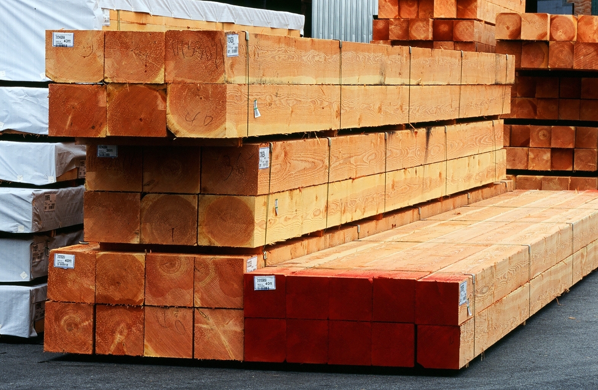 Exterior daytime image of strapped bundles of square cross section heavy timbers ready for transport