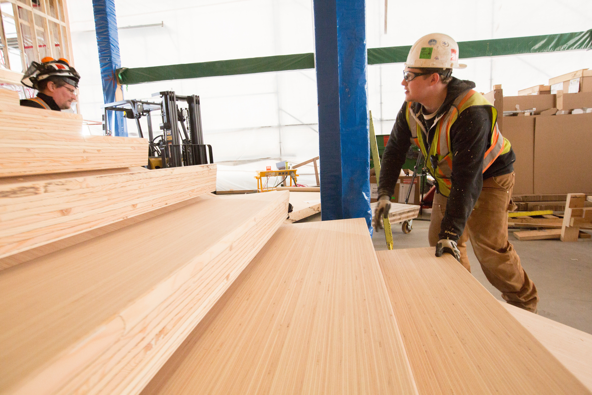 Laminated veneer lumber (LVL) being used in the prefabrication construction of stair treads and risers by workers wearing PPE
