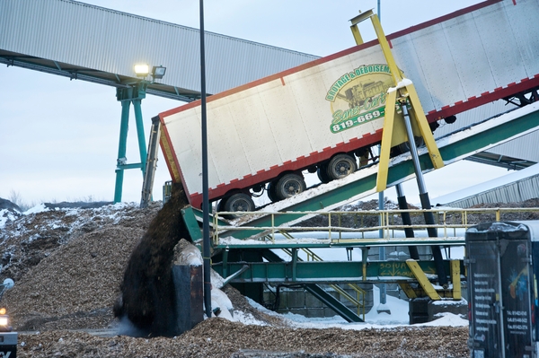 Outdoor daytime image of semi trailer on hydraulic tilt platform while unloading Northern Softwood Kraft (NSK), an unbleached structurally strong pulp, used for kraft and wrapping papers, specialty papers and linerboard